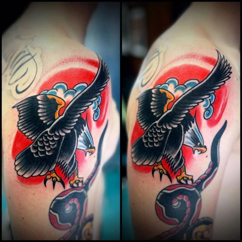 Colorful tattoo on the upper arm featuring an eagle with a snake.