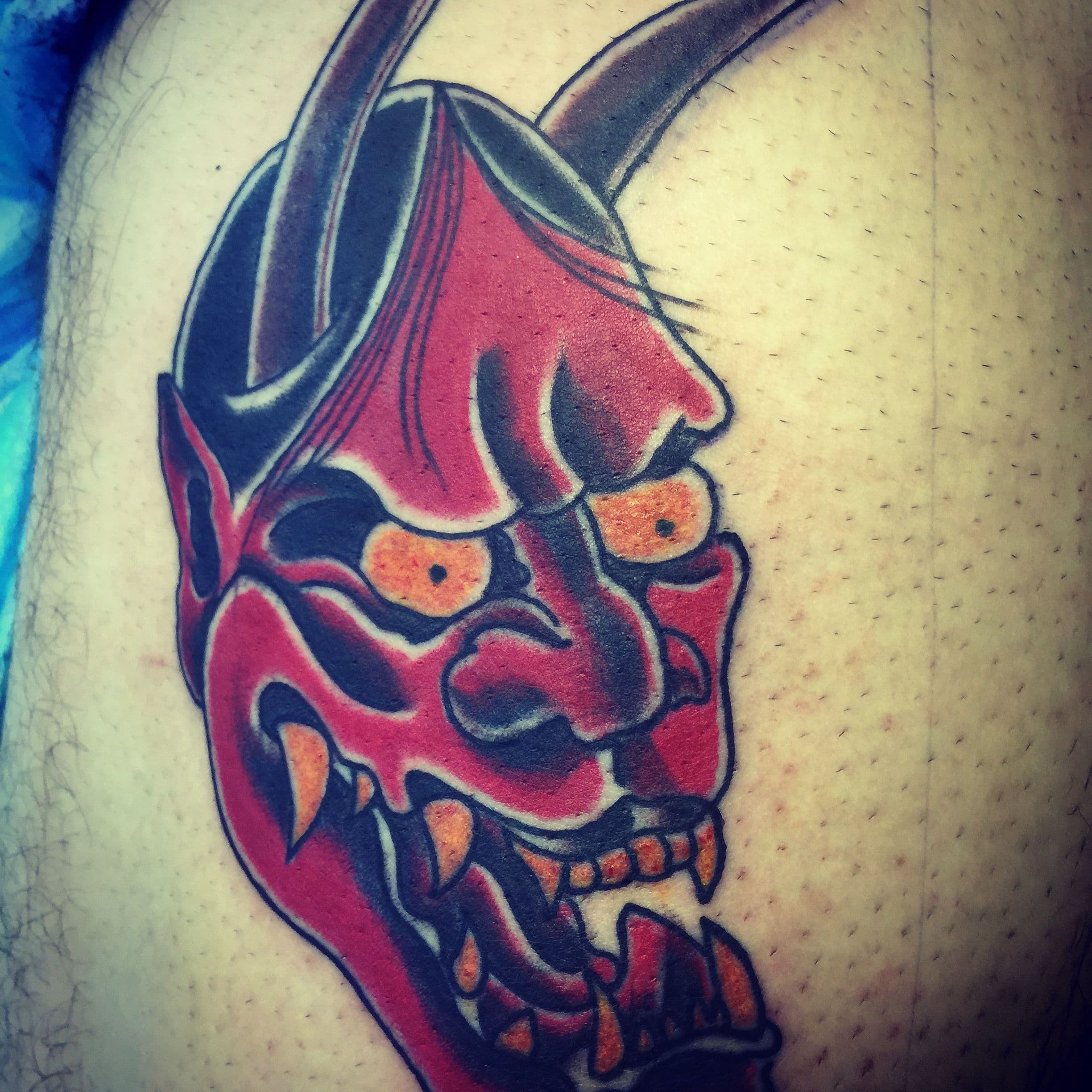 Japanese Oni mask tattoo on the thigh with vibrant colors