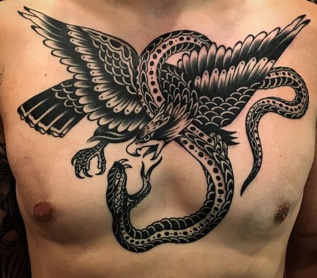 Tattoo of an eagle and snake entangled on a person's chest.