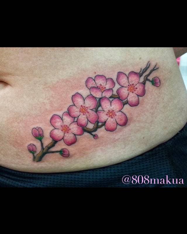 Cherry blossom branch tattoo on the torso.