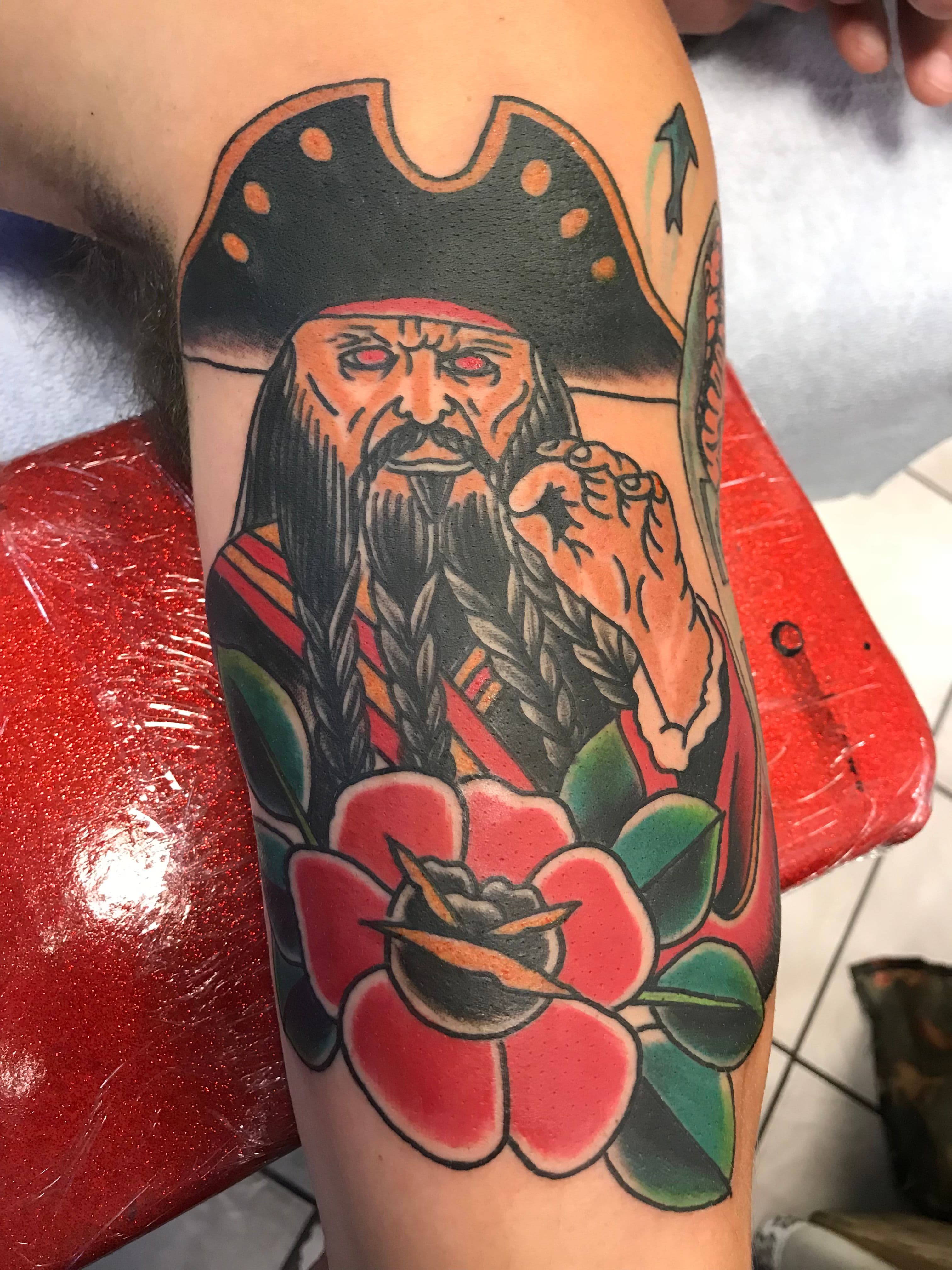 Tattoo of a pirate and a rose on the upper arm.